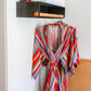 Photo of two cotton red blue yellow green striped serape robes hanging on a clothes bar inside of Austin Motel room