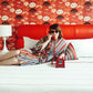 Woman lounging on Austin Motel bed wearing cotton striped serape robe and heart shaped sunglasses holding a cord phone to her ear
